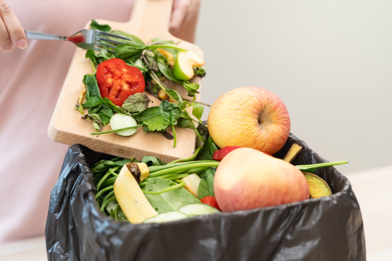 Conceito de ambiente de resíduos alimentares, pessoa a deitar lixo alimentar para o caixote do lixo